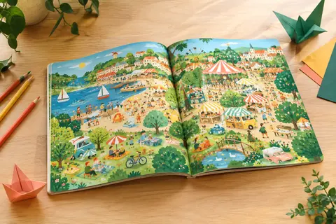 Album cherche-et-trouve tout-carton ouvert sur une table claire, accompagné de crayons de couleur